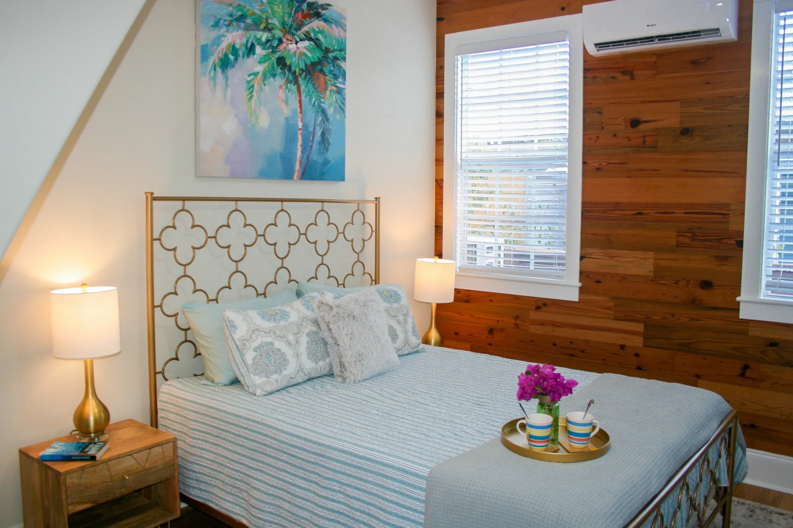 Cozy bedroom with decorative pillows and painting.
