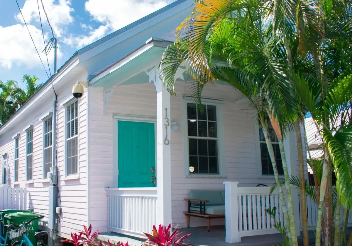 White house with teal door and plants.